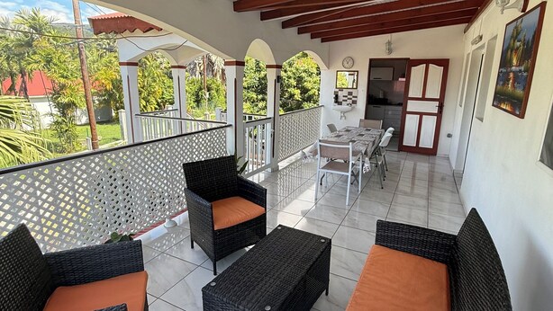 A covered patio area with wicker furniture and a view of the surrounding greenery. - Villa nanou, quiet villa top with small sea view (BOUILLANTE)
