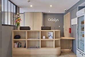 A reception area with a wooden desk, a vase with flowers, a refrigerator, and a wall-mounted sign reading "Odaly's". - Bel Appartement spacieux lumineux, près du centre (Dijon)