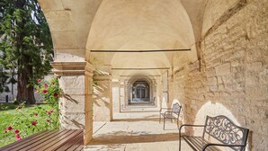 Un couloir voûté en pierre, doté de bancs et d’un sentier.