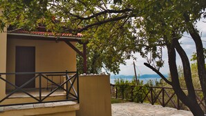 Un bâtiment doté d’un patio carrelé en pierre, d’un balcon avec une rambarde en métal et offrant une vue sur la mer.