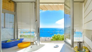A balcony with a view of the sea, a blue bowl, a yellow bowl, and a metal grater.