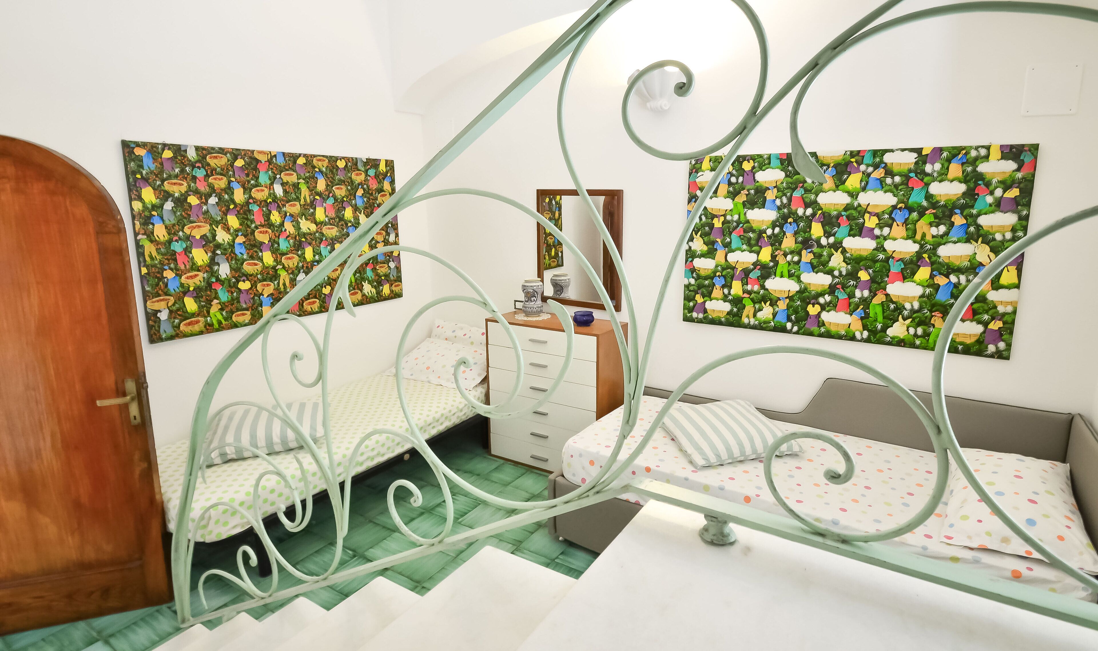 A bedroom with a bed, a dresser, and two wall-mounted paintings.