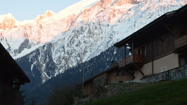 Eine Bergeshütte mit Balkon mit Blick auf ein verschneites Gebirge.