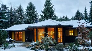 Een huis bedekt met sneeuw, met grote ramen en een terras.