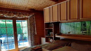 Een gezellige slaapkamer met een groot bed, een inbouwkast en een raam met uitzicht op een bos.