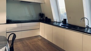 Una cucina moderna con mobili bianchi, un piano di lavoro nero, una finestra e un piano cottura integrato.