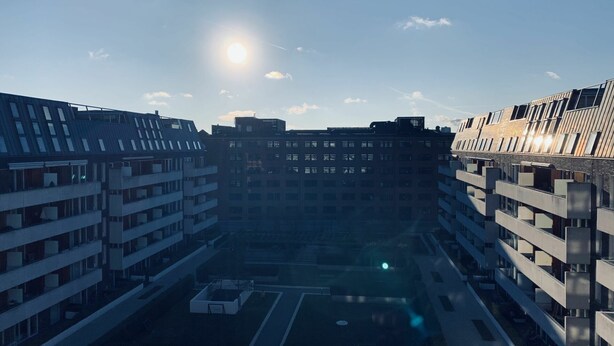 Un edificio moderno a più piani con un cortile centrale, caratterizzato da balconi e un design con tetto piatto.