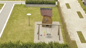 Un’area giochi con altalene, una sabbiera e una casetta per uccelli.