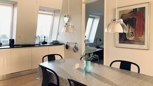 Una cucina moderna con zona pranzo, caratterizzata da un'ampia finestra, luci a sospensione e un quadro appeso al muro.