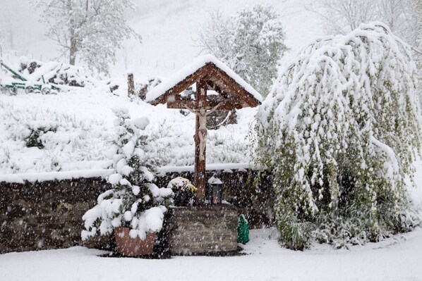 A wooden gazebo with a snow-covered roof, surrounded by snow-laden trees and bushes. - Cozy apartment with mountain views in a quiet location, suitable for families (Tresdorf)