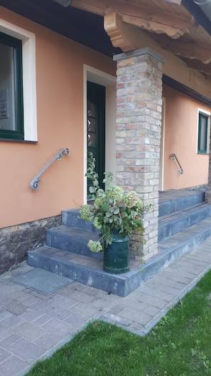 A house with a brick column, a green door, and a potted plant on the steps. - Landlust Bergsdorf - pure relaxation! (Bergsdorf)
