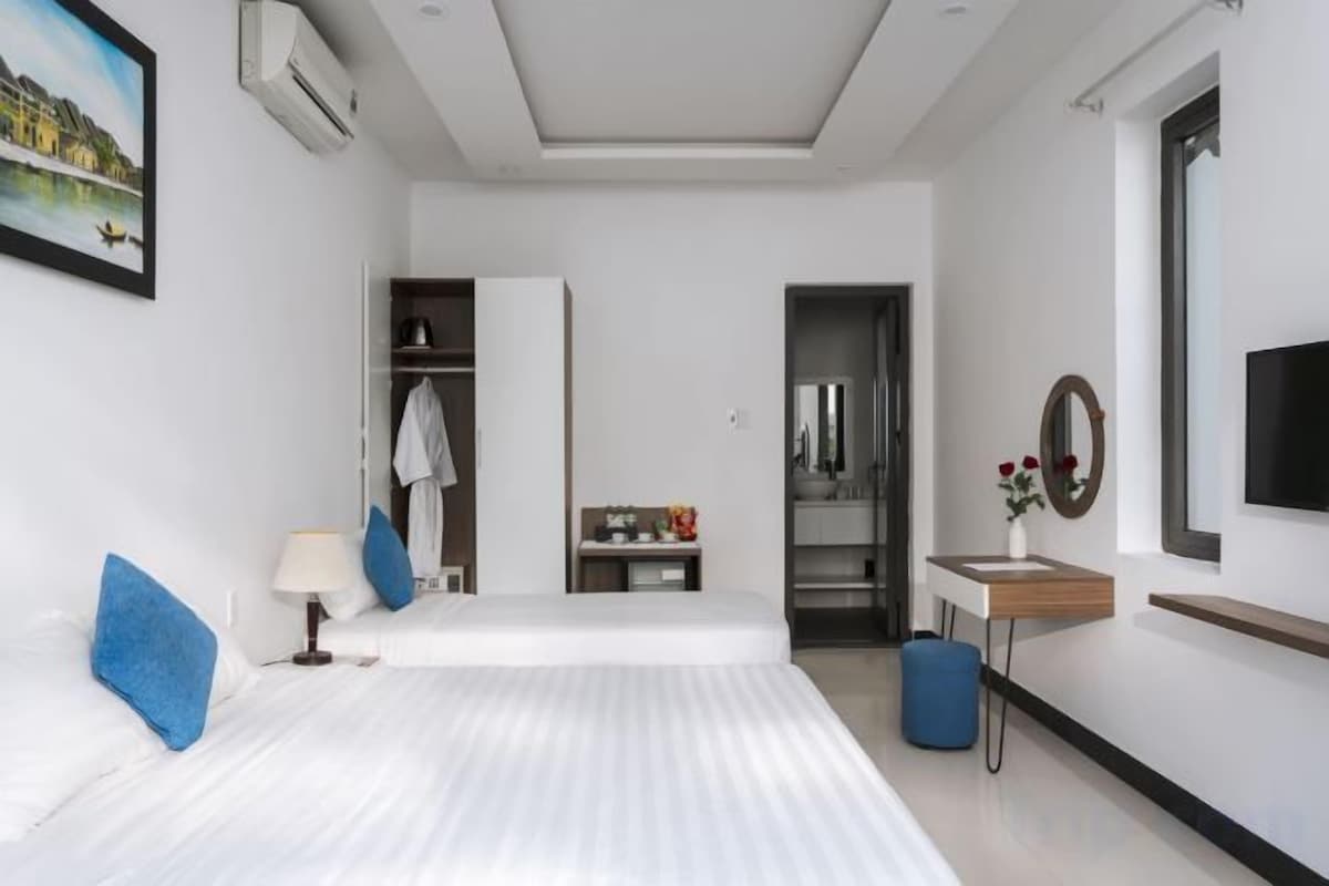 A modern hotel room with a bed, bedside table, lamp, and a view of the cityscape.