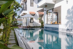 Een buitenzwembad, parasols bij het zwembad en ligstoelen