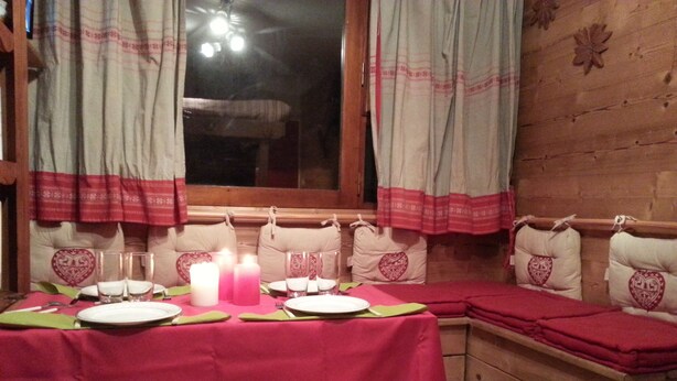 A cozy dining area with a table set for two, featuring heart-shaped pillows and a pink tablecloth. - Furnished studio rental Winter/Summer Savoie ski area at the foot of the slopes (Villarembert)