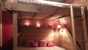 A wooden bunk bed with a ladder, a small shelf with candles, and a wall-mounted lamp. - Furnished studio rental Winter/Summer Savoie ski area at the foot of the slopes (Villarembert)