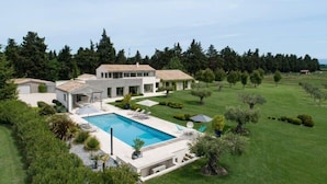 Una casa moderna amb piscina, envoltada d'un jardí ben cuidat i arbres.