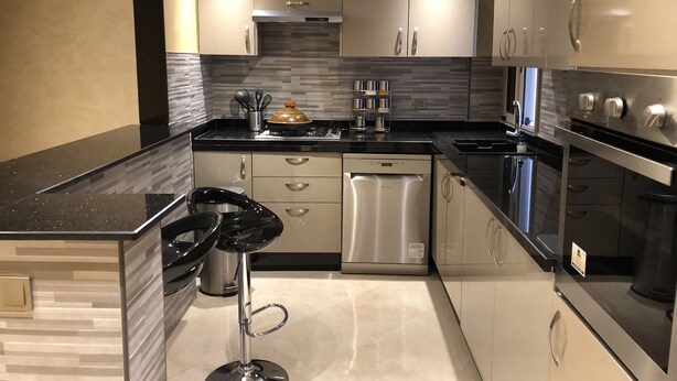 Een moderne keuken met roestvrijstalen apparatuur, een vaatwasser en een barstoel.