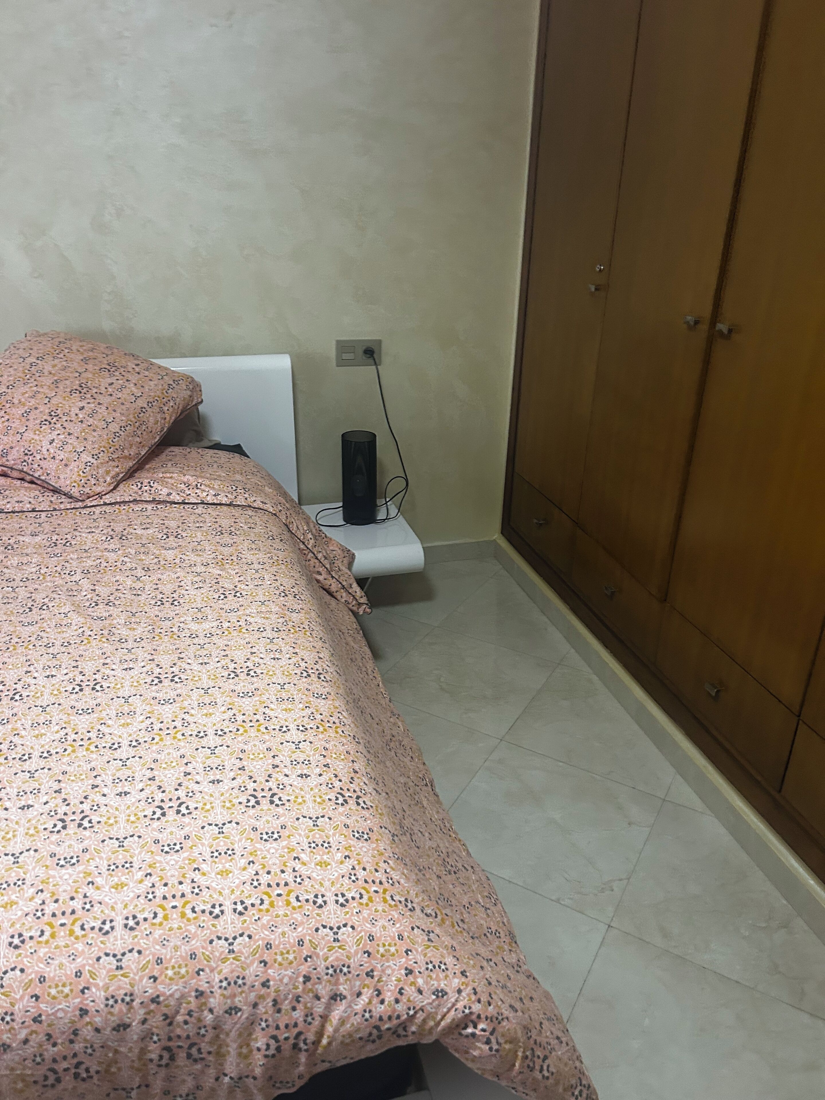 A bedroom with a bed, a bedside table, a lamp, and a wardrobe.