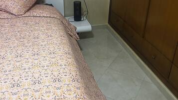 A bedroom with a bed, a bedside table, a lamp, and a wardrobe.