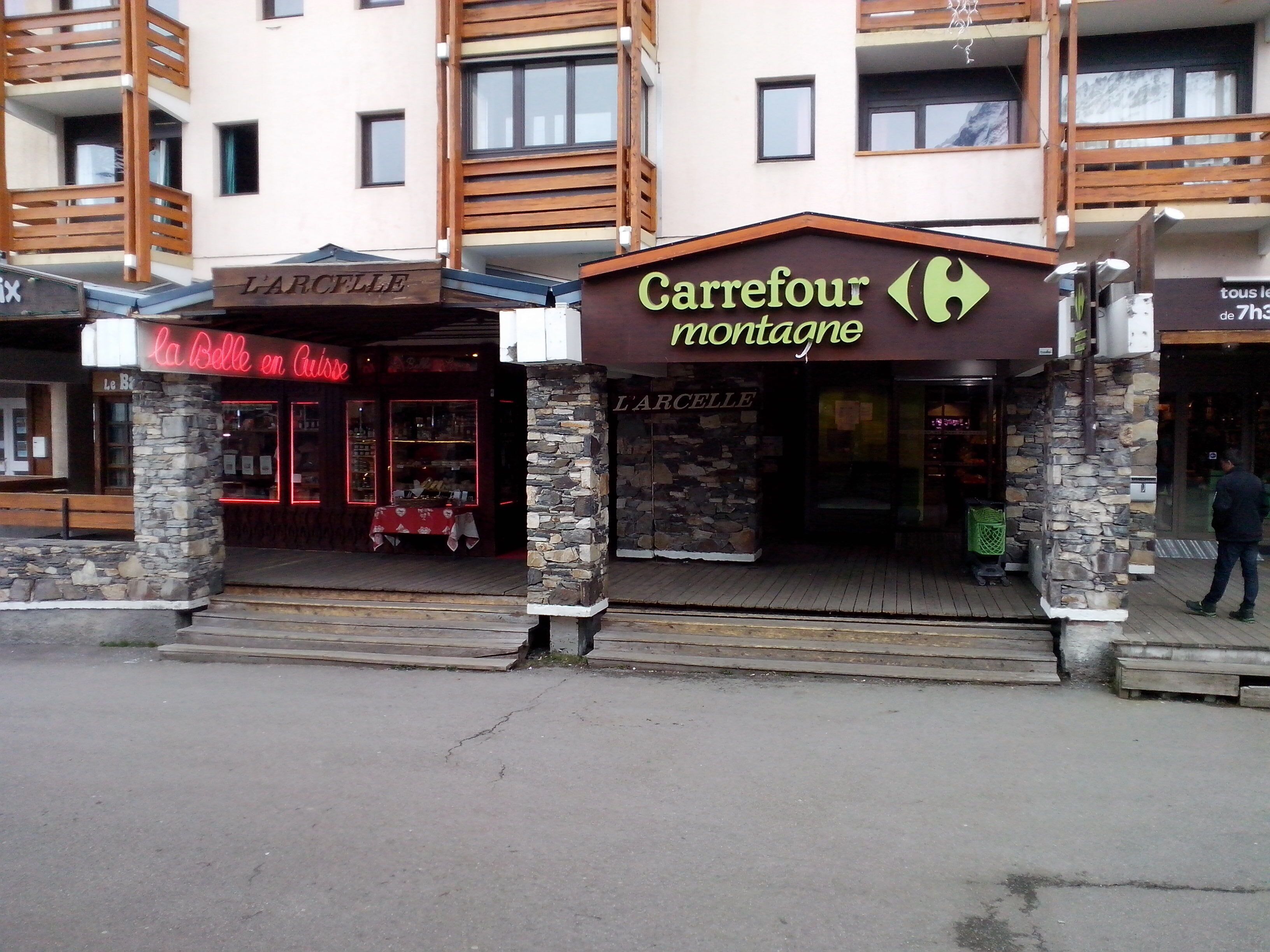 Una fachada con un cartel que dice "Carrefour montagne" y otro cartel para "L'Arcelle en Caisse".