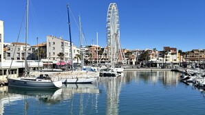 A marina with boats docked, a Ferris wheel, and buildings in the background.