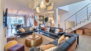 A modern living room with a sofa set, a coffee table, and a staircase.