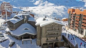 Un centro de esquí cubierto de nieve con un gran albergue y un edificio moderno con balcones.