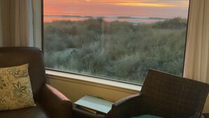 A room with a large window offering a view of a sunset over a grassy landscape. - Magical Place By The Sea. (Watsonville)