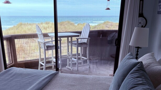A bedroom with a large sliding glass door leading to a balcony with a view of the ocean and beach. - Magical Place By The Sea. (Watsonville)