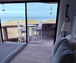 A bedroom with a large sliding glass door leading to a balcony with a view of the ocean and beach. - Magical Place By The Sea. (Watsonville)