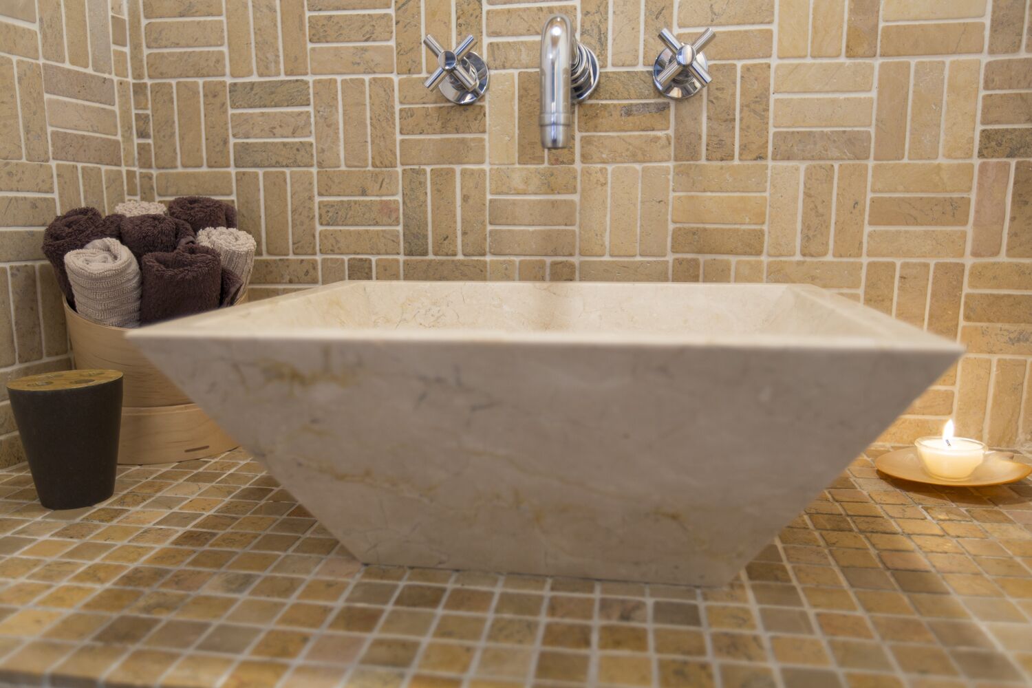 A large, freestanding bathtub in a bathroom with a tiled floor and a brick wall.