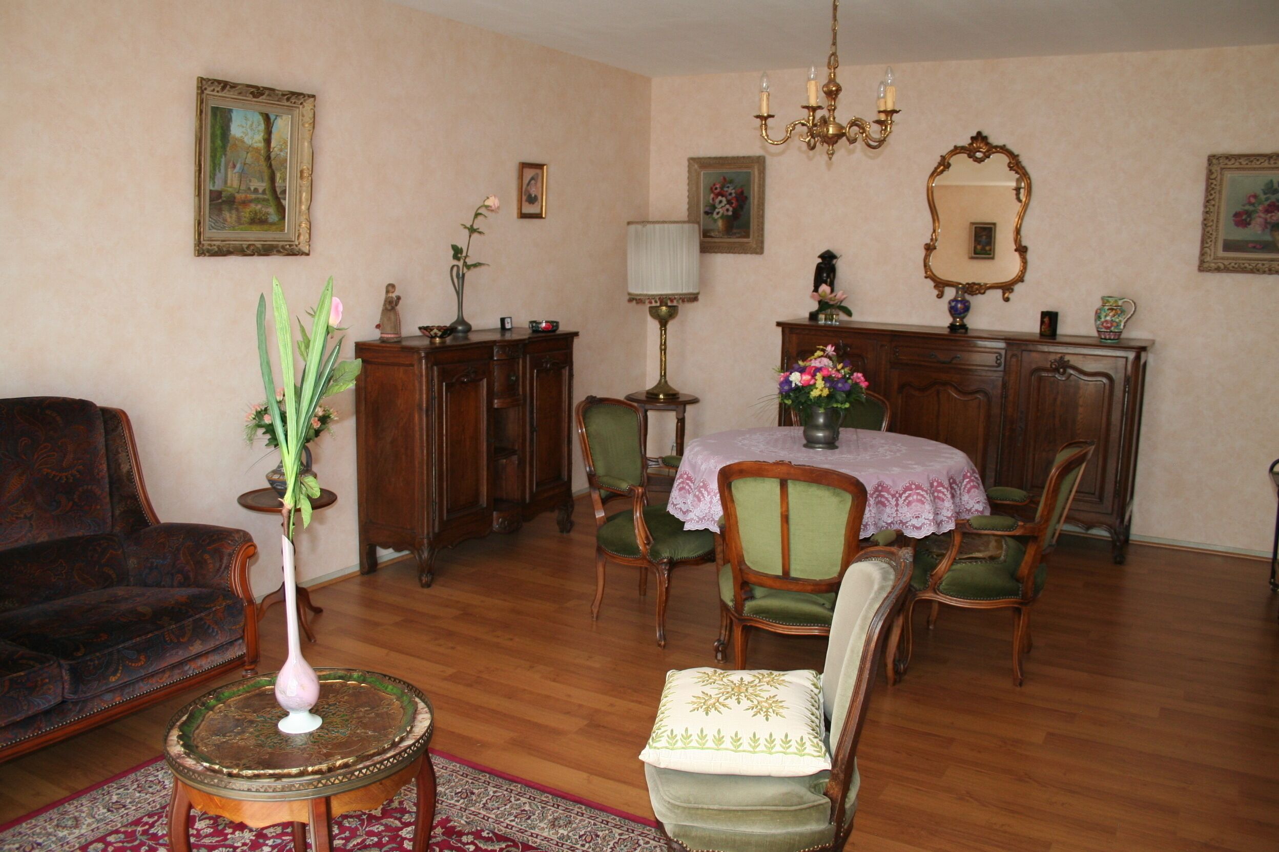 Un salon traditionnel avec un canapé, une table à manger et des chaises, un lustre et une cheminée.