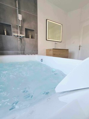 Een bad/douchecombinatie, een haardroger, handdoeken, zeep