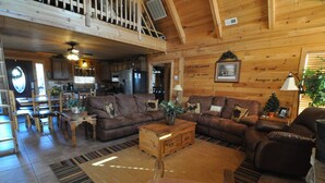 Un intérieur chaleureux de chalet en bois, comprenant un salon, un coin repas et une cuisine.