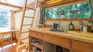 Una cocina con encimera de madera, un lavamanos y un ventanal con vistas a la vegetación.