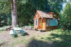 Eine kleine Holzhütte mit Veranda, umgeben von Bäumen.