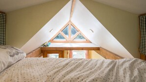 Un dormitorio con techo inclinado y un ventanal saliente.