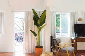 Ein Wohnzimmer mit einer großen Pflanze, einem Fernseher und einem Sessel.