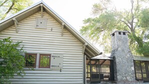 A log cabin with a stone chimney and a covered porch. - On the Beach, Teddy Roosevelt Stayed Here. Pet friendly, large fenced property (Pass Christian)