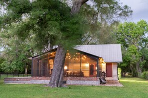 A modern house with a large glass front, a stone base, and a tree in front. - On the Beach, Teddy Roosevelt Stayed Here. Pet friendly, large fenced property (Pass Christian)