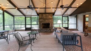A covered patio with a stone fireplace, outdoor seating, and string lights. - On the Beach, Teddy Roosevelt Stayed Here. Pet friendly, large fenced property (Pass Christian)