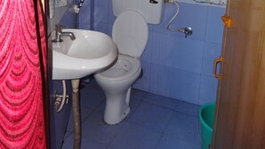 A bathroom with a toilet, a shower area, and a sink. - For Delightful stay visit us. (Madikeri)