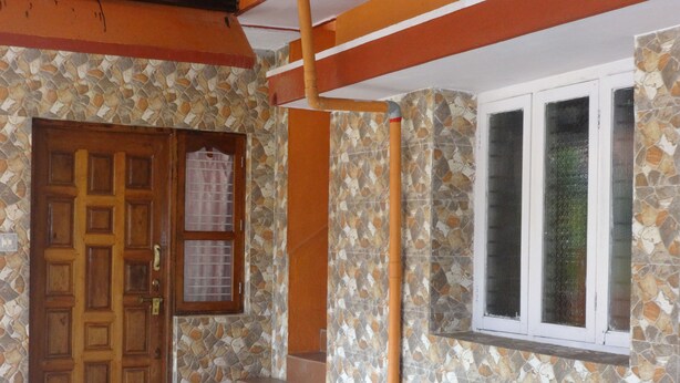A wooden door with a window above it, a set of stairs leading up to the door, and a wall with a mosaic pattern. - For Delightful stay visit us. (Madikeri)