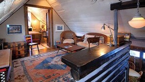 Acogedor cuarto ático con techo inclinado, un banco de madera, sofá, una mesita y una alfombra estampada.