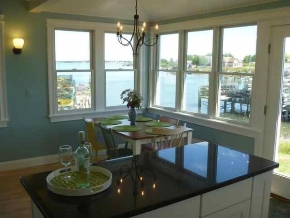 Un comedor con vista al agua, un candelabro y una mesa dispuesta con un jarrón y platos.