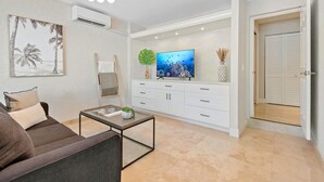 Un salon comprenant un canapé, une table basse, un téléviseur et des meubles de rangement.