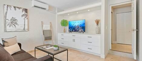 A living room with a sofa, coffee table, TV, and cabinets.