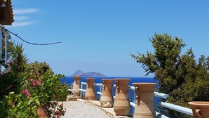 Terracotta pots arranged on a balcony overlooking a coastal view with a mountain in the distance. - villa fully equipped with swimming pool and sea view and 360 °  (kamilari)