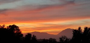 A sunset over mountains with silhouettes of trees in the foreground. - villa fully equipped with swimming pool and sea view and 360 °  (kamilari)