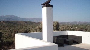 A rooftop terrace with a bird sculpture, seating area, and a view of the surrounding landscape. - villa fully equipped with swimming pool and sea view and 360 °  (kamilari)